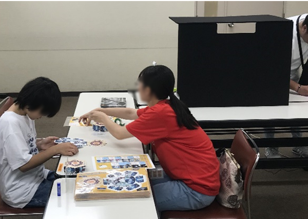 分光器づくりに取り組むお子さんと、丁寧に対応しているボランティアさん