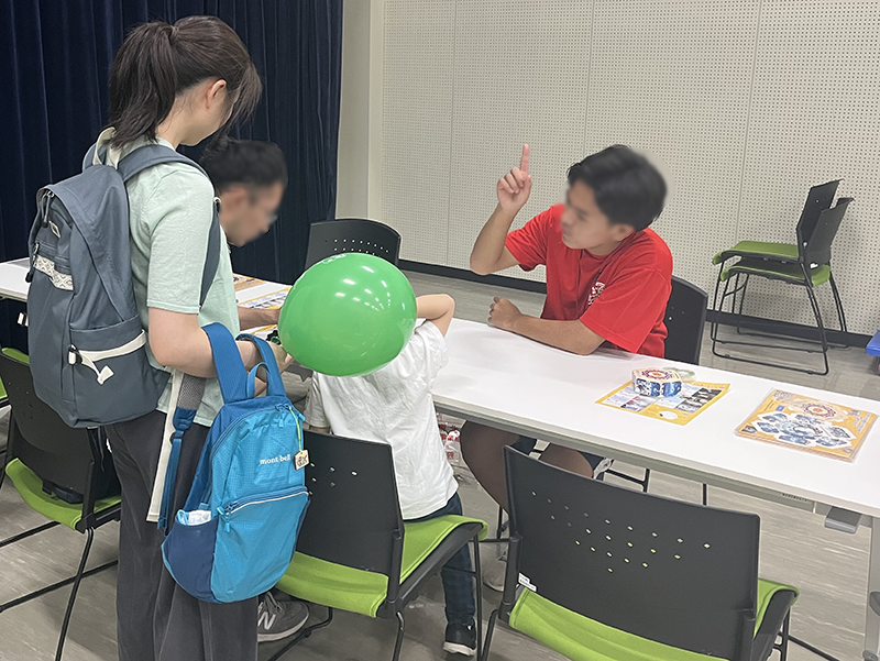 分光器づくりに取り組むお子さんと、優しく対応しているボランティアさん