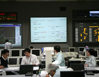photo:制御室スクリーンでチェックシートを確認する実験責任者と制御室連絡員