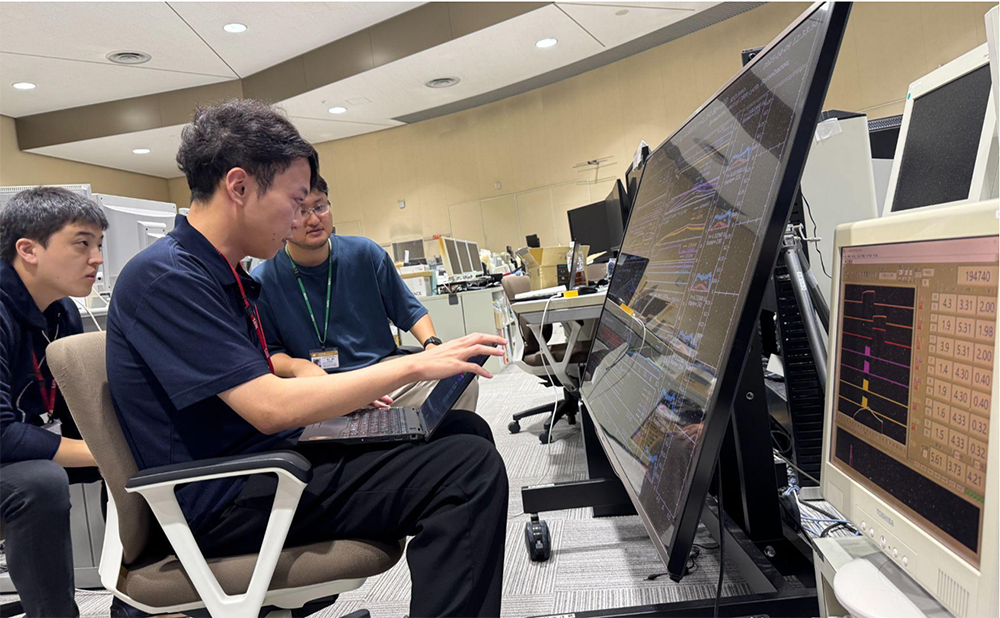 大学院生である鈴木優也氏（総合研究大学院大学先端学術院核融合科学コース、上の写真中央奥）