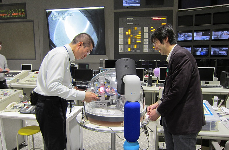 制御室でアバター（中央）に向け説明を行う永岡教授（左）と伊藤准教授（右）