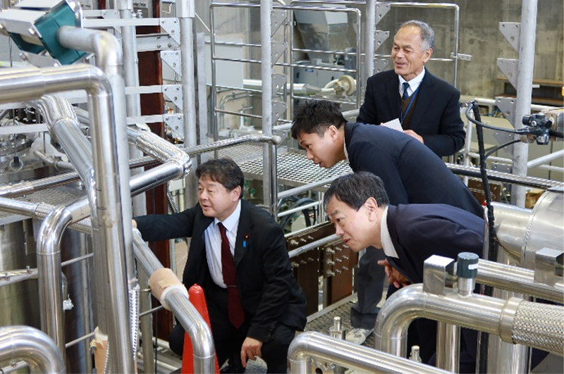 超伝導マグネット研究棟で説明を受ける
若山政務官(左)